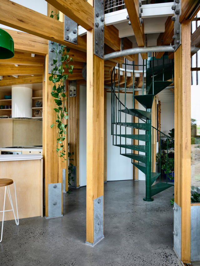 A green perforated metal spiral staircase connects the two levels