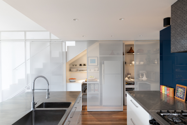 Perforated screens conceal under-stair storage in the kitchen