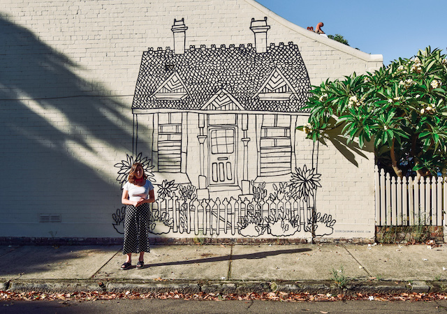 Georgia in front of the mural she painted on the side of her parents' house