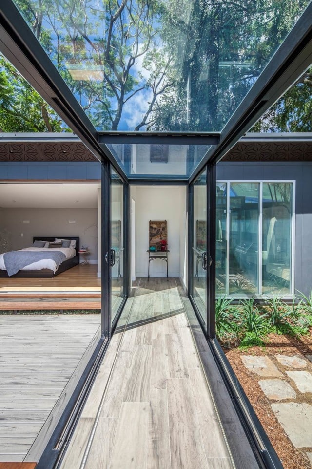 An indoors-outdoors hallway, featuring glass sliding doors, by Justin Loe Architects