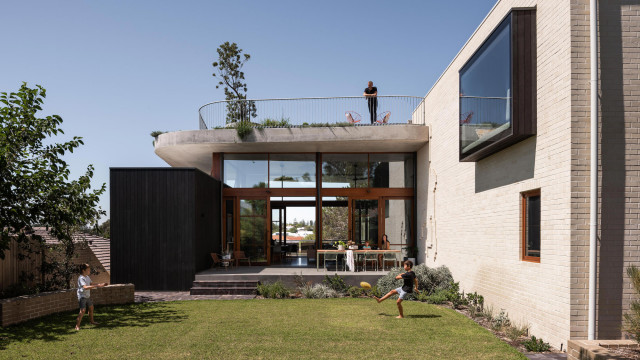 The home's second level features a living area that flows out onto a garden as well as a balcony that overlooks a pool