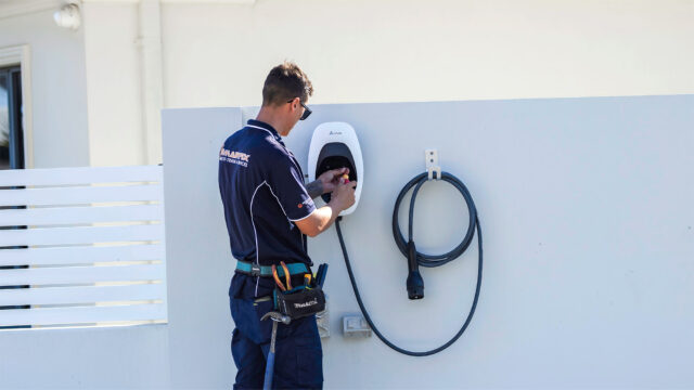 Electrician installing an EV charger wall unit during a home electrical upgrade 